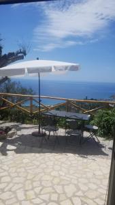 an umbrella and a picnic table with the ocean in the background at La Terrazza Del Duca in Marina di Camerota