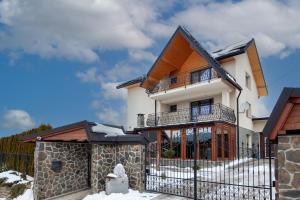 uma casa com uma cerca na neve em Apartament na wzgórzu em Muszyna