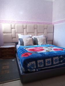 uma cama com um cobertor azul e almofadas em salwa em Ifrane