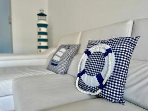 un sofá blanco con almohadas azules y blancas y un faro en NEW! Apartamento con 2 piscinas, parque infantil, a 1 min de la playa, en Sant Antoni de Calonge