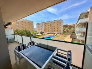 een balkon met een tafel en stoelen en een zwembad bij NEW! Apartamento con 2 piscinas, parque infantil, a 1 min de la playa in Sant Antoni de Calonge