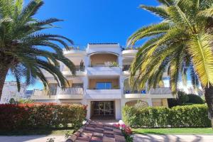 um grande edifício branco com palmeiras em frente em Cannes Marina vue sur le port em Mandelieu-la-Napoule