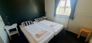 2 łóżka w małym pokoju z oknem w obiekcie Gistihús Hólmavíkur w mieście Hólmavík