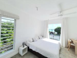Dormitorio blanco con cama y ventana grande en Cozy pavillon with private jacuzzi on rooftop terrace - Jolly's Rock, en Grand Gaube