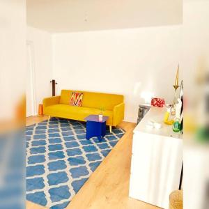 ein Wohnzimmer mit einem gelben Sofa und einem blauen Teppich in der Unterkunft Cosy house in Guingamp ! in Guingamp