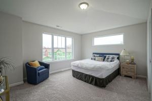 a bedroom with a bed and a blue chair at DreamPlace Bana Home in Indianapolis