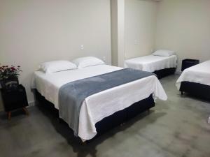 um quarto com 2 camas e lençóis brancos em Pousada Premiatto em Holambra