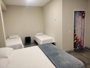 um quarto com duas camas e uma porta com uma pintura em Pousada Premiatto em Holambra