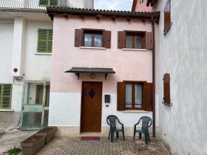 two chairs sitting outside of a house with a door at Al centro e vicina al lago in Farra dʼAlpago
