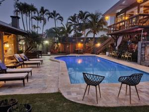 a swimming pool with chairs and a house at Pousada Villa Caiobá in Matinhos