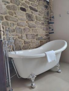 a bath tub in a bathroom with a stone wall at Villa Carmen in András