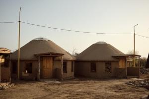 dwa domy z dachem krytym strzechą w wiosce w obiekcie Altyn Oimok Yurt Camp w mieście Tong
