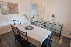 a dining room with a table with chairs and a vase of flowers at Home In Harrow/Wembley in Harrow on the Hill