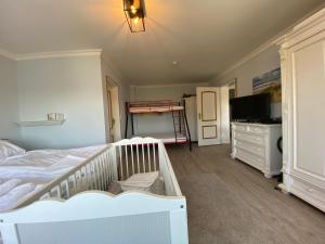 1 dormitorio con cuna, cama y TV en Casa Raphael direkt am Scharbeutzer Strand, en Scharbeutz