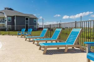 a row of blue lounge chairs in front of a fence at Peaceful Seaside Condo-Walking Path to the Beach in Corpus Christi
