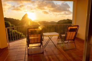 two chairs and a table on a balcony with the sunset at Belle Etoile in Soufrière