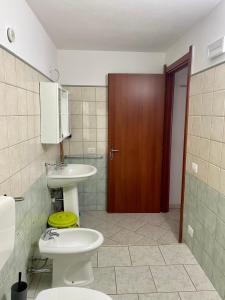 a bathroom with a sink and a toilet and a door at L'Oasi di Chia in Chia