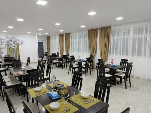 una sala da pranzo con tavoli e sedie neri e sedie e chairsktop di Casa Bianca Pensiune a Târgu Jiu