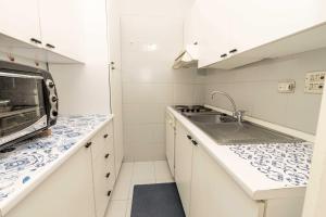 cocina blanca con fregadero y microondas en Confortevole Bilocale Giardino Doppio Parcheggio, en Punta Ala