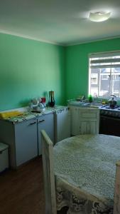 uma cozinha com paredes verdes, uma mesa e uma janela em Cabaña con tinaja, piscina, quincho em Valdivia