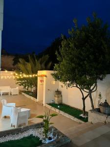 un patio con sillas blancas y árboles por la noche en Le Tre Rose di Roberta, en Alezio