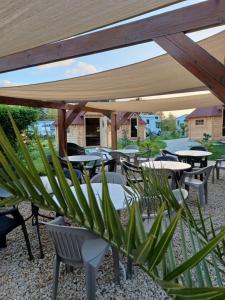 a patio with tables and chairs under a canopy at Camping le Vallage in Attigny