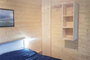 a bedroom with a wooden wall with a bed and shelves at Chalet avec terrasse face aux Pyrénées in Bartrés