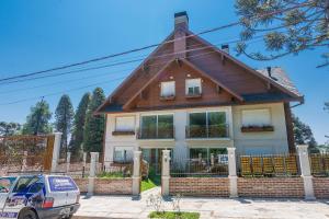 una casa con techo de gambrel con un coche aparcado delante en Apto Vivere - Stay House Temporada, en Canela