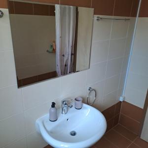 a bathroom with a white sink and a mirror at Dimitris place near Athens airport in Koropíon