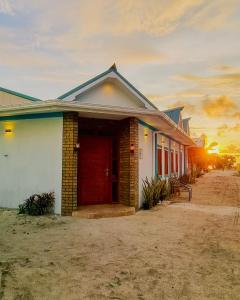 a house with a red door with the sunset in the background at Vaagali Inn in Keyodhoo