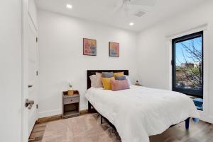a white bedroom with a large bed and a window at Nest Away 2 Queen near EWR-Penn- Free Parking in Newark