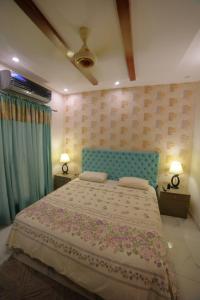 una camera con un grande letto con testiera blu di Grey Orchard Homestay - A Family Place a Lahore