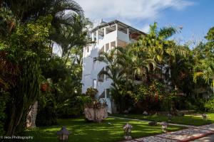 un bâtiment blanc avec des palmiers devant lui dans l'établissement Hotel Ciudad Blanca, à Copan Ruinas