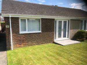 a brick house with a lawn in front of it at Highthel Holiday Home by the Northumberland Coast in Morpeth