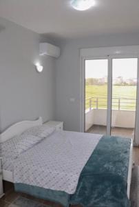 a white bedroom with a bed and a balcony at FAMILY-FRIENDLY APARTMENTS in Donji Štoj