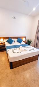 a bedroom with two beds with blue pillows at Vaagali Inn in Keyodhoo