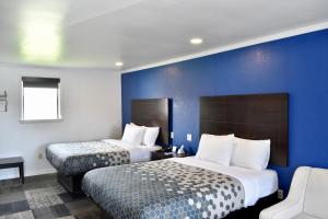 a hotel room with two beds and a blue wall at Rodeway Inn in Swainsboro