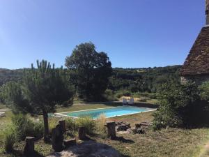 una piscina in un campo vicino a una casa di La ferme de Roquedure a Montfaucon