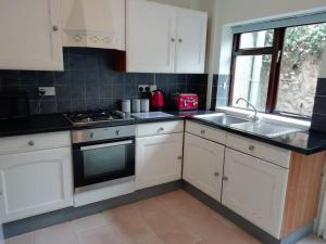 a kitchen with white cabinets and a sink and a window at Haverfordwest terraced home in Pembrokeshire