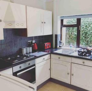 a kitchen with white cabinets and a stove and a sink at Haverfordwest terraced home in Pembrokeshire