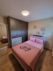 1 dormitorio con 1 cama rosa y 2 toallas en CASA DI NIMA, en Ioannina