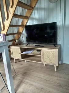 a living room with a large television on a table at Gîte chalet bleu soleil in Saint-Benoît-dʼHérbertot