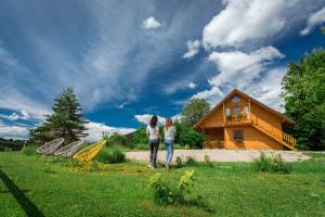 two women standing in the grass in front of a house at Ranch Jelov Klanac in Rakovica