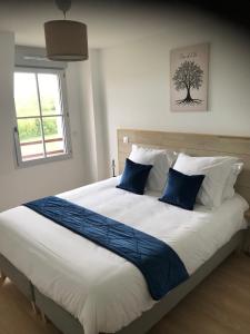 sypialnia z dużym łóżkiem z niebiesko-białymi poduszkami w obiekcie Le Saint Pierre en Baie Appt 3-4 pers parking privé w mieście Saint-Valéry-sur-Somme