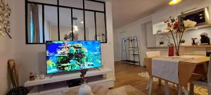 sala de estar con TV de pantalla plana en la pared en Le Pourpre en Chelles
