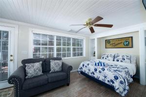 ein Schlafzimmer mit einem Bett, einem Sofa und einem Deckenventilator in der Unterkunft Pirates Pointe Resort in Ruskin