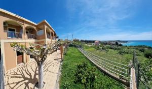 a house with a tree next to the ocean at Nikos Apartments Corfu in Agios Stefanos