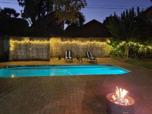 una piscina con chimenea en el patio trasero por la noche en Roosthaven Guesthouse, en Centurion