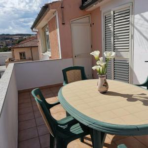stół z krzesłami oraz waza z kwiatami na balkonie w obiekcie La casa di Alessia w mieście Santa Teresa Gallura +27 zdjęć