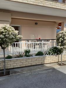uma varanda de um edifício com uma mesa e flores em Xrysafis Apartments em Nea Vrasna